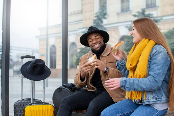 Two young adults eating snacks at the airport in winter time